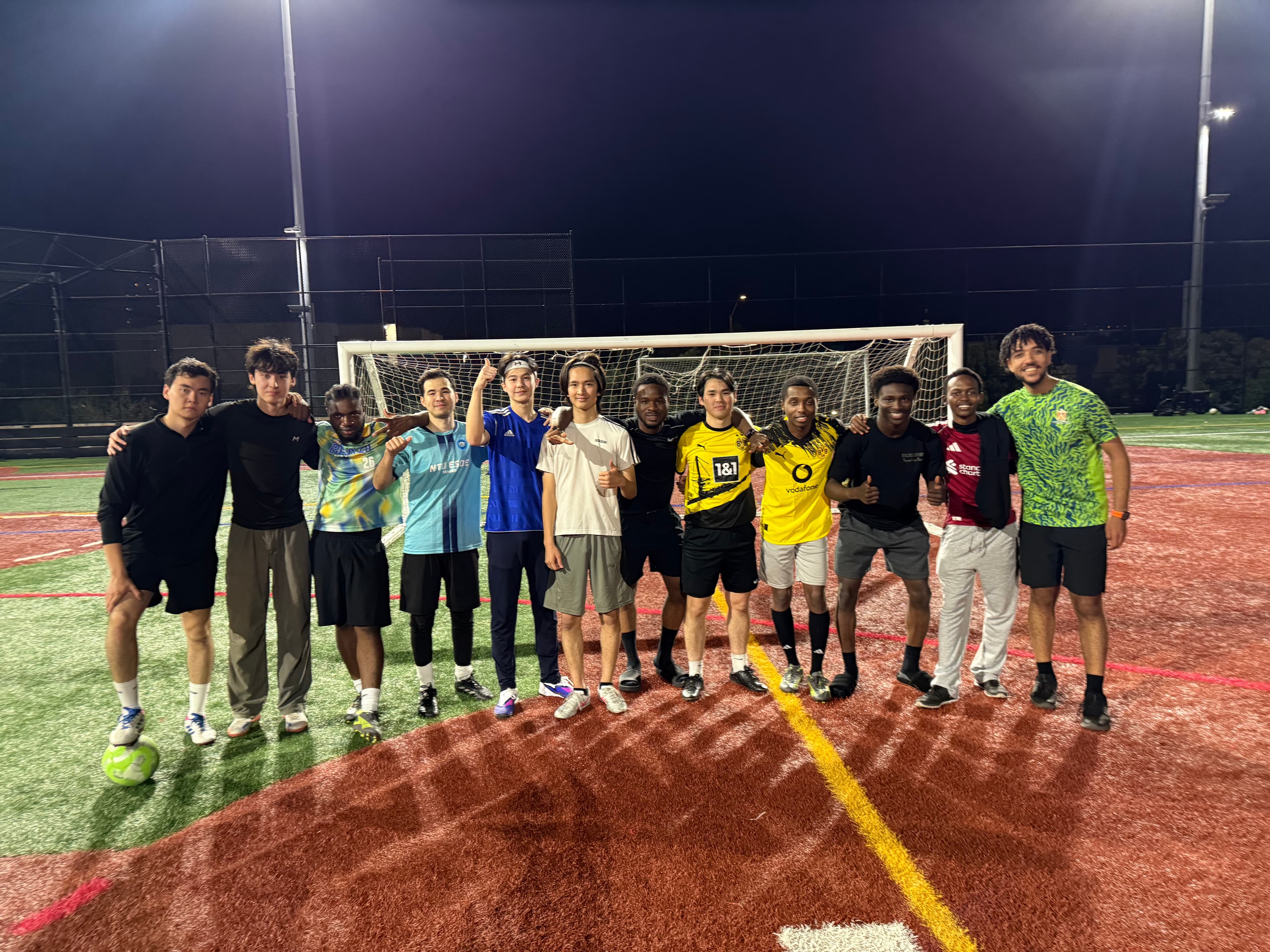 A group posing in front of a soccer goal on a floodlit field